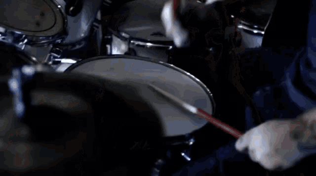 a close up of a person playing a drum set with a cymbal in the foreground