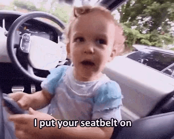 a little girl is sitting in the driver 's seat of a car .