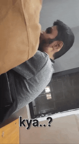 a man with a beard is sitting at a table with the words kya.. written on the bottom