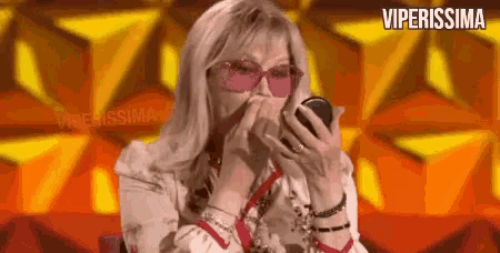 a woman wearing pink sunglasses is applying makeup to her face .