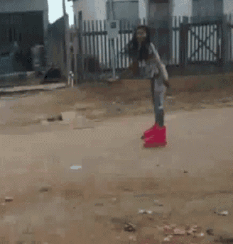 a woman wearing pink boots is standing on a dirt road .