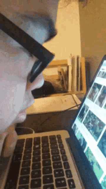 a man wearing glasses is looking at a laptop computer