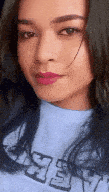 a close up of a woman 's face wearing a blue shirt with the letter y on it