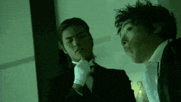 a man in a tuxedo and white gloves looks at his reflection