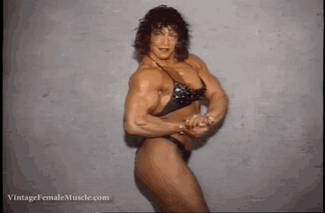 a female bodybuilder in a black bikini is posing for a photo .