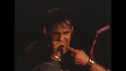 a man is singing into a microphone while wearing a harley davidson t-shirt .