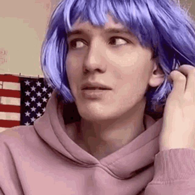 a woman wearing a purple wig and a pink hoodie .