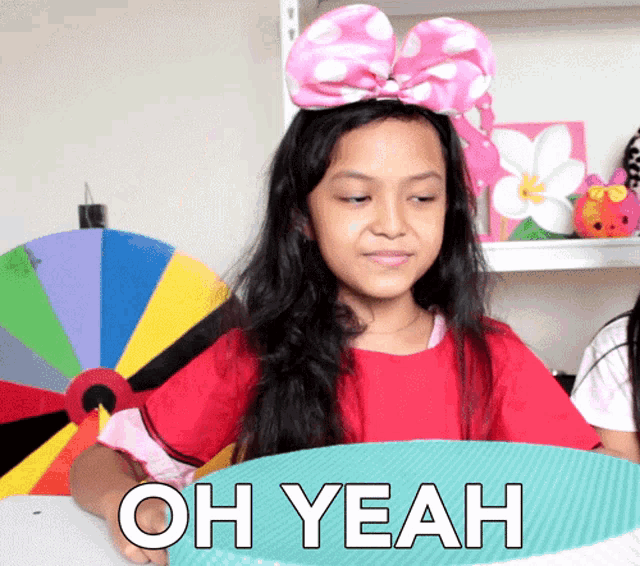 a little girl with a pink bow on her head is holding a sign that says oh yeah