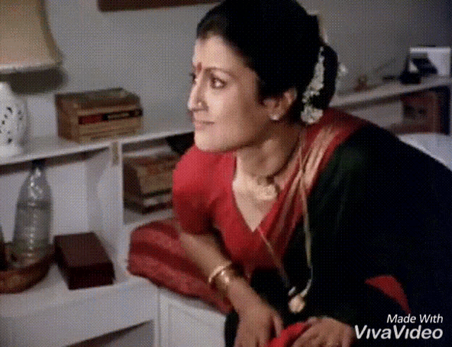 a woman in a red and green saree is sitting on a couch and made with vivavideo