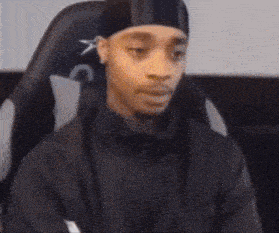 a person is sitting in a chair with their arms crossed and making a funny face .