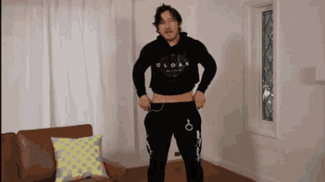 a man in a cloak hoodie is standing in front of a couch