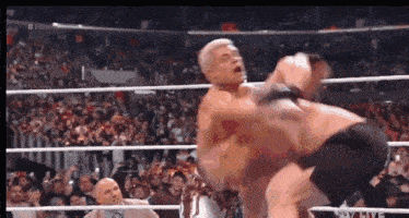 a couple of men are wrestling in a ring in front of a crowd .