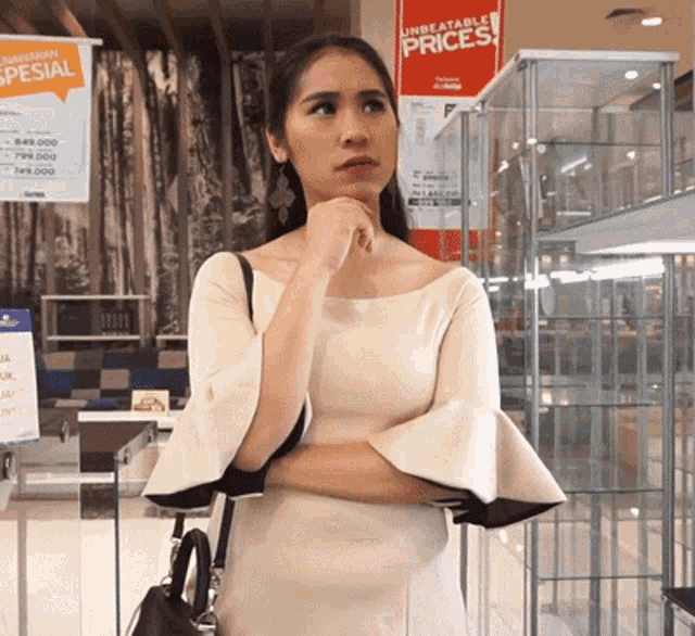 a woman in a white dress is standing in front of a sign that says unbeatable prices
