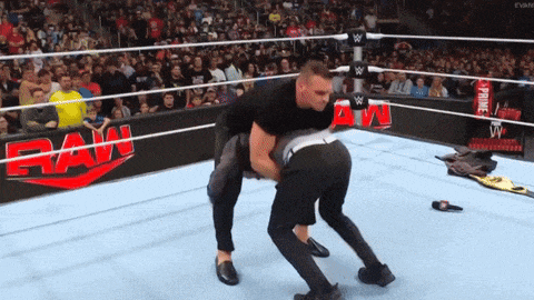 a man is carrying another man in a wrestling ring that says raw on the side