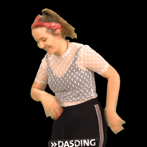 a woman wearing a polka dot shirt and black pants is dancing with a sign that says dasding