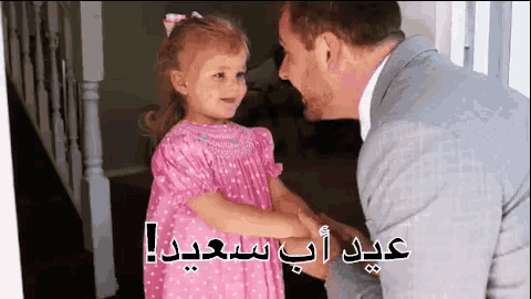a little girl in a pink dress holds hands with a man in a suit