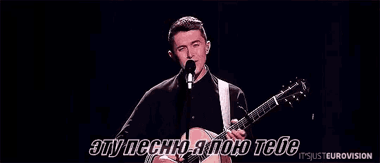 a man is playing a guitar and singing into a microphone .