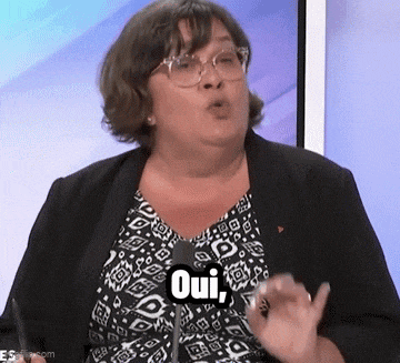a woman wearing glasses is talking into a microphone and saying oui