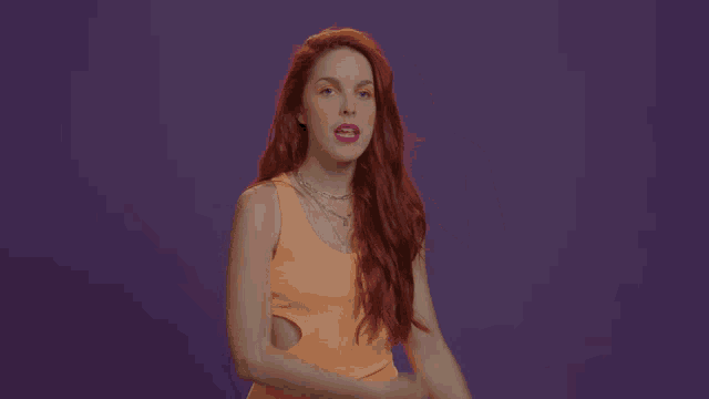 a woman with red hair is wearing an orange tank top and a necklace