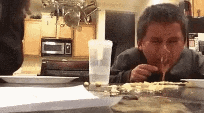 a man is sitting at a table in a kitchen eating a piece of food .
