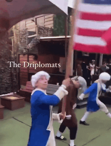 a group of men dressed in colonial costumes are dancing in front of an american flag with the words " the diplomats " written above them