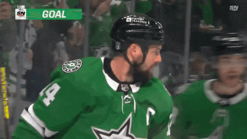 two hockey players are celebrating a goal with a sign that says goal on it