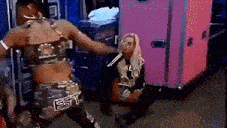 a woman in a camouflage outfit is kneeling down next to another woman in a pink suitcase .