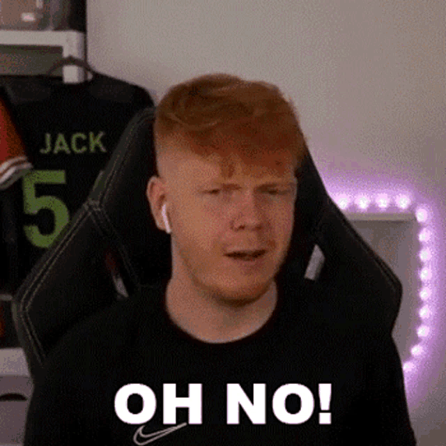 a man with red hair and a beard is sitting in a gaming chair with headphones on .