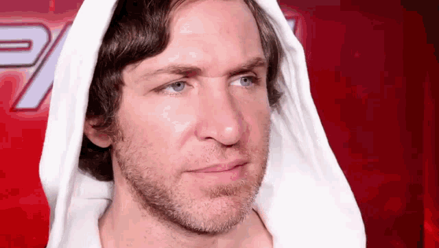 a man with a beard and blue eyes wearing a white hoodie .