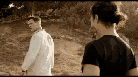 a man in a white shirt and a woman in a black shirt are standing in a field