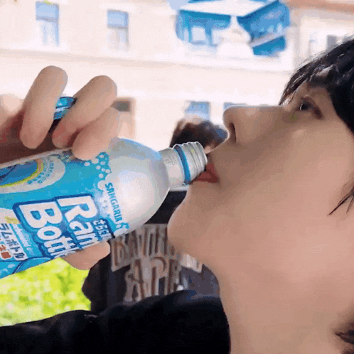 a person drinking a bottle of rain bottle water