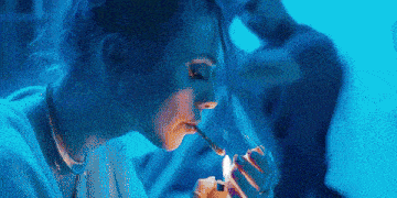 a woman is lighting a cigarette with a lighter in her hand .