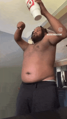 a man without a shirt is holding a q cup up in the air