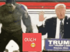 a man in a suit stands next to a man in a hulk costume