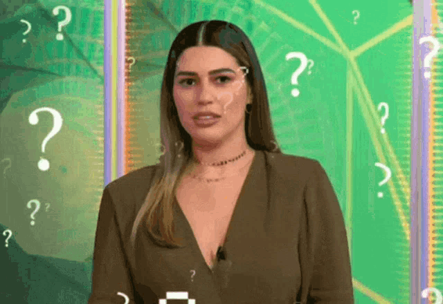 a woman stands in front of a green background with question marks