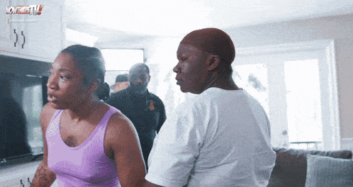 a woman in a purple tank top is standing next to a man in a white shirt with a police officer standing behind them