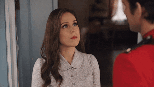 a man in a red uniform is talking to a woman in a white shirt