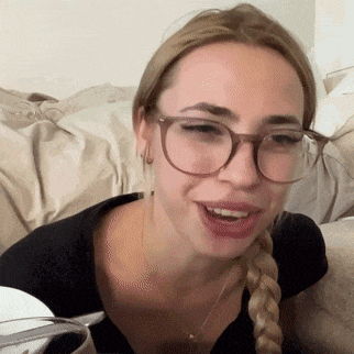 a woman wearing glasses and a braided ponytail is smiling