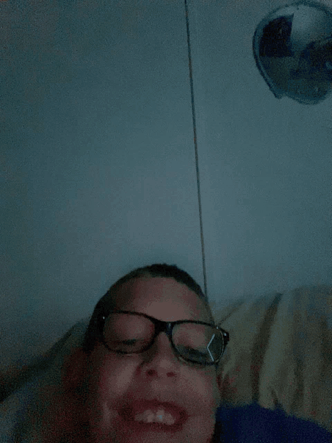 a young boy wearing glasses is smiling in front of a balloon