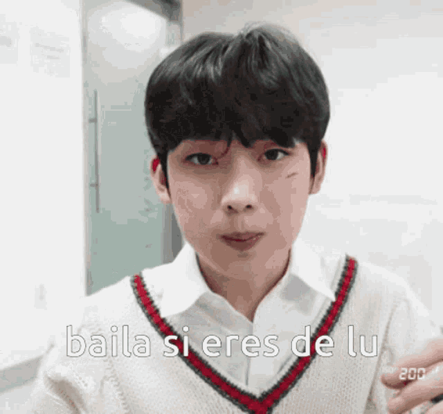a young man wearing a white shirt and sweater says baila si eres de lu .