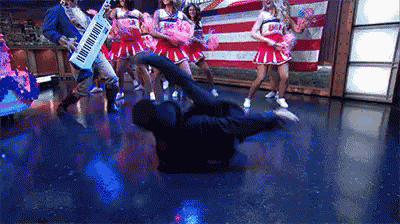 a man is laying on the floor in front of cheerleaders and a piano