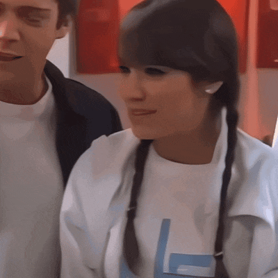 a woman wearing a white shirt with the letter l on it stands next to a man