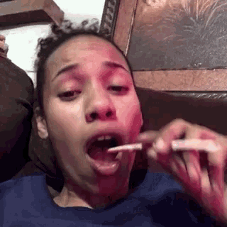 a woman in a blue shirt is eating something with a spoon