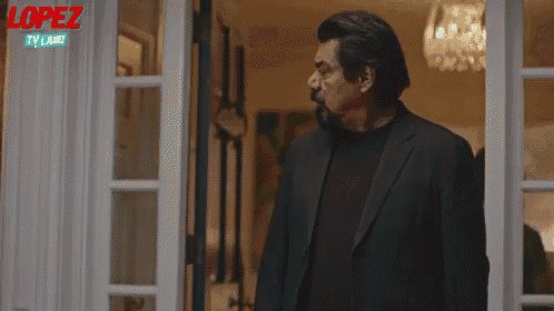 a man in a suit is standing in front of a door in a living room .