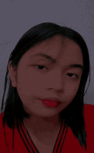 a close up of a woman 's face with a red shirt on and red lipstick .