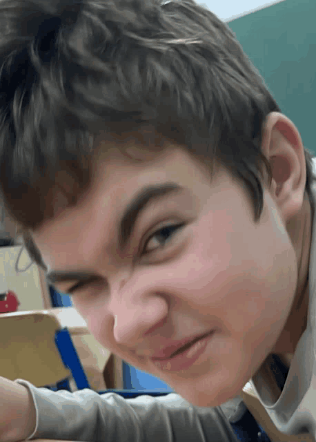 a close up of a boy making a funny face with his eyes closed