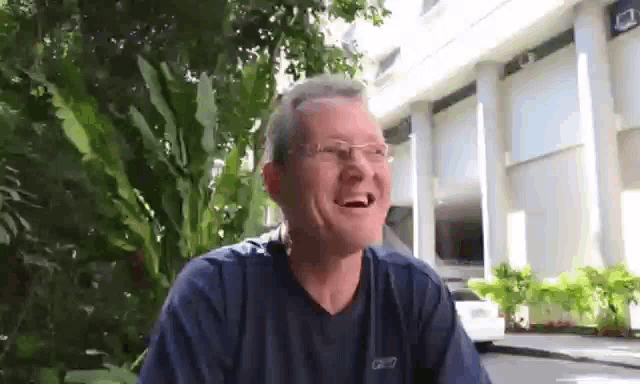 a man wearing glasses is smiling in front of a building .