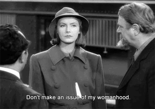 a woman in a hat stands in front of two men with the caption " don 't make an issue of my womanhood "