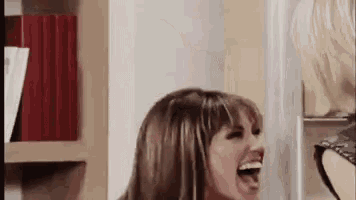 a woman is laughing with her mouth open while standing next to another woman .