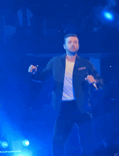 a man singing into a microphone on a stage with blue lights